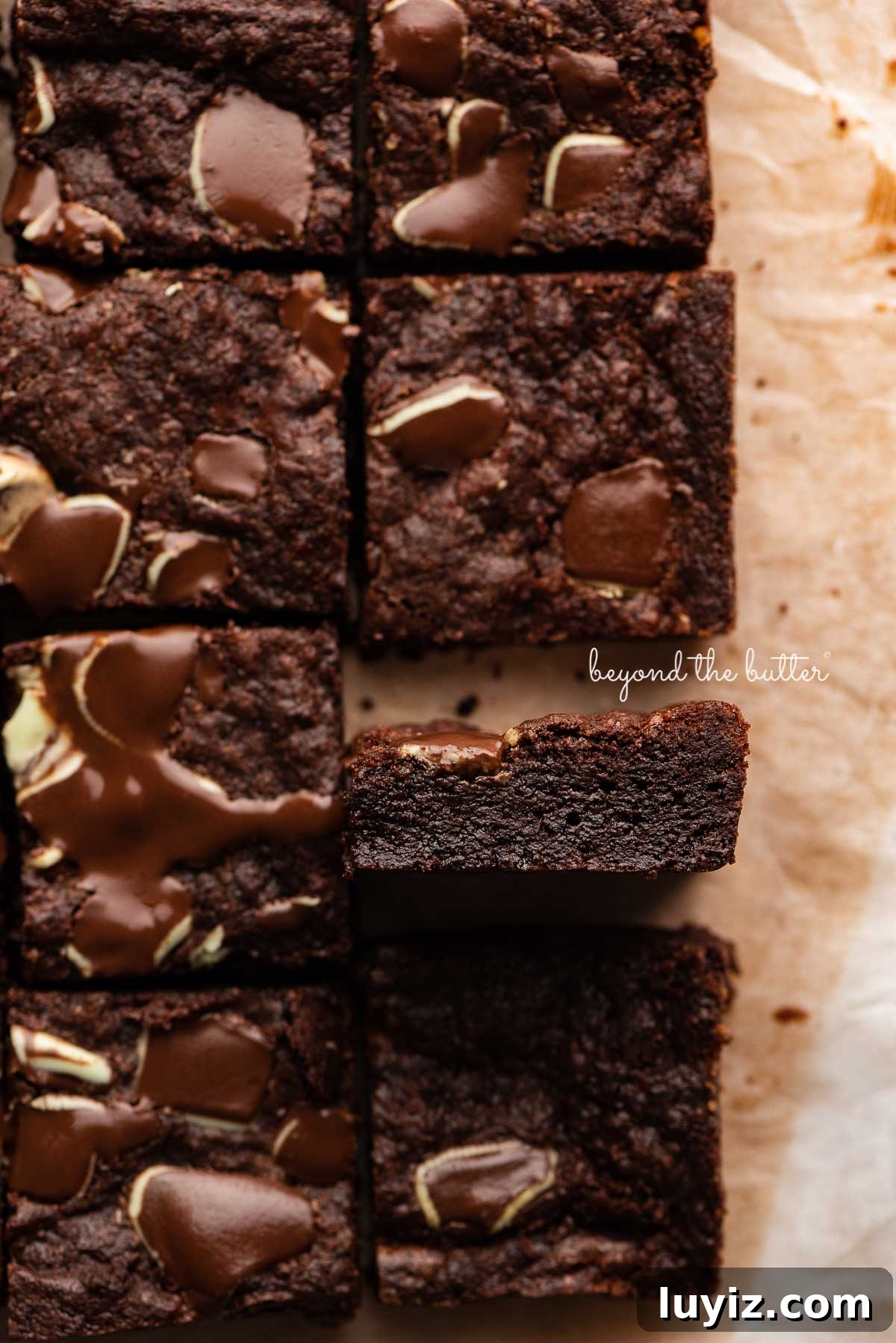 Decadent Double Chocolate Mint Brownies Recipe 5 Double chocolate mint brownies on brown parchment paper background with the center brownie on its side | © Beyond the Butter®