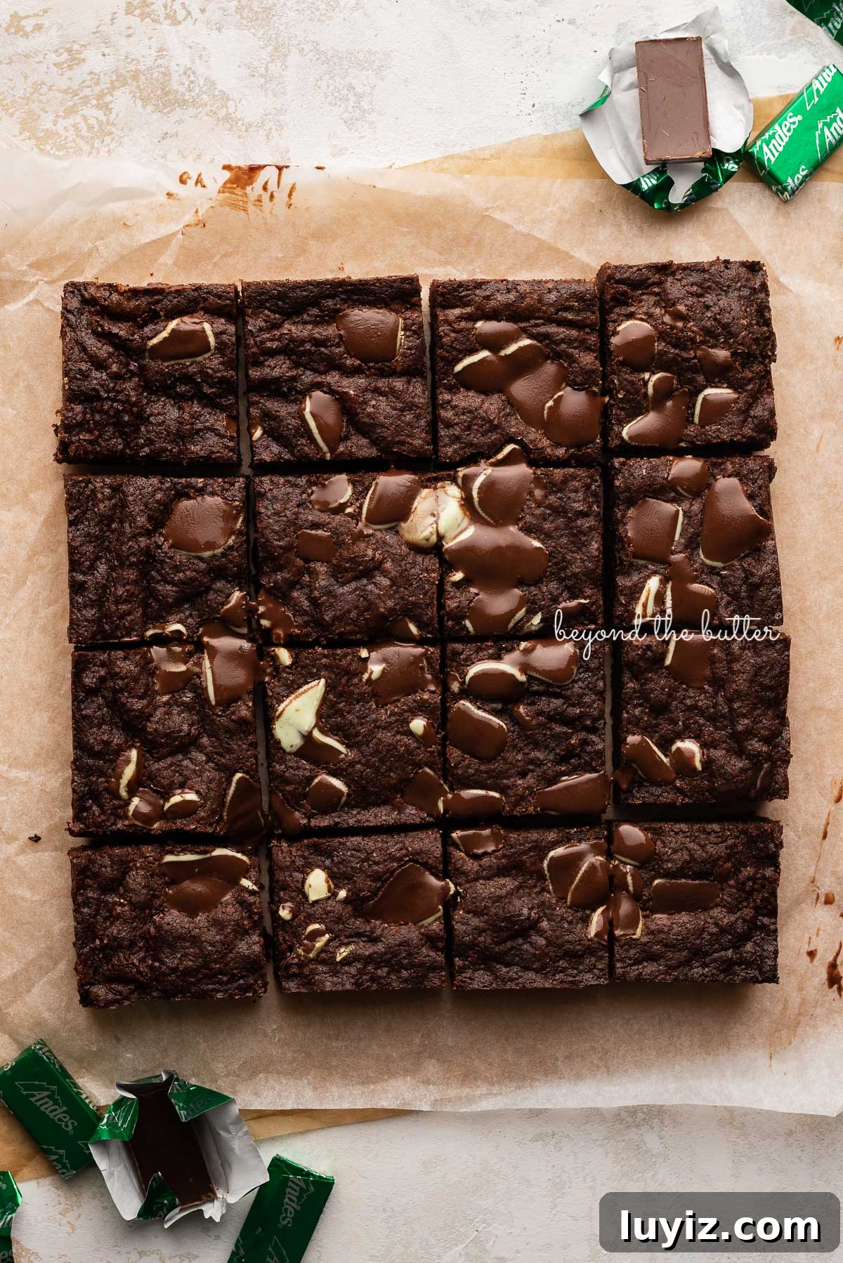 Decadent Double Chocolate Mint Brownies Recipe 7 Just cut double chocolate mint brownies on brown and white sheets of crumbled parchment paper with andes mints around them | © Beyond the Butter®