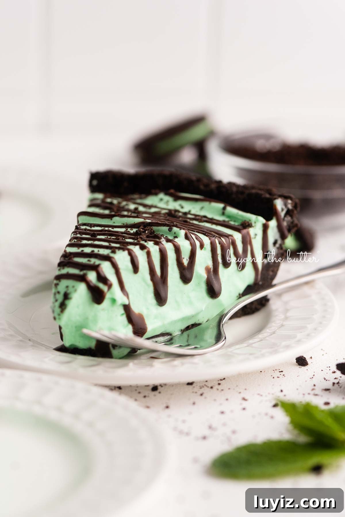 No-Bake Mint Chocolate Pie Recipe — Cool Mint Chocolate Delight 4 Dessert plates with slices of no bake mint chocolate pie with chocolate syrup drizzled over the top | © Beyond the Butter®