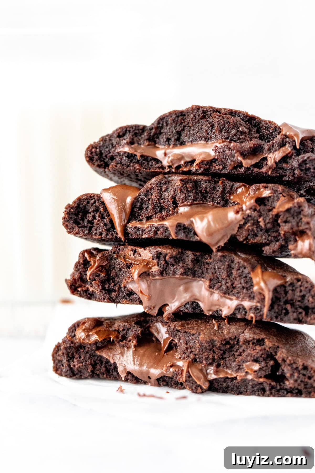 Nutella-Filled Double Chocolate Cookies 2 Nutella stuffed chocolate cookies broken in half and placed one on top of another
