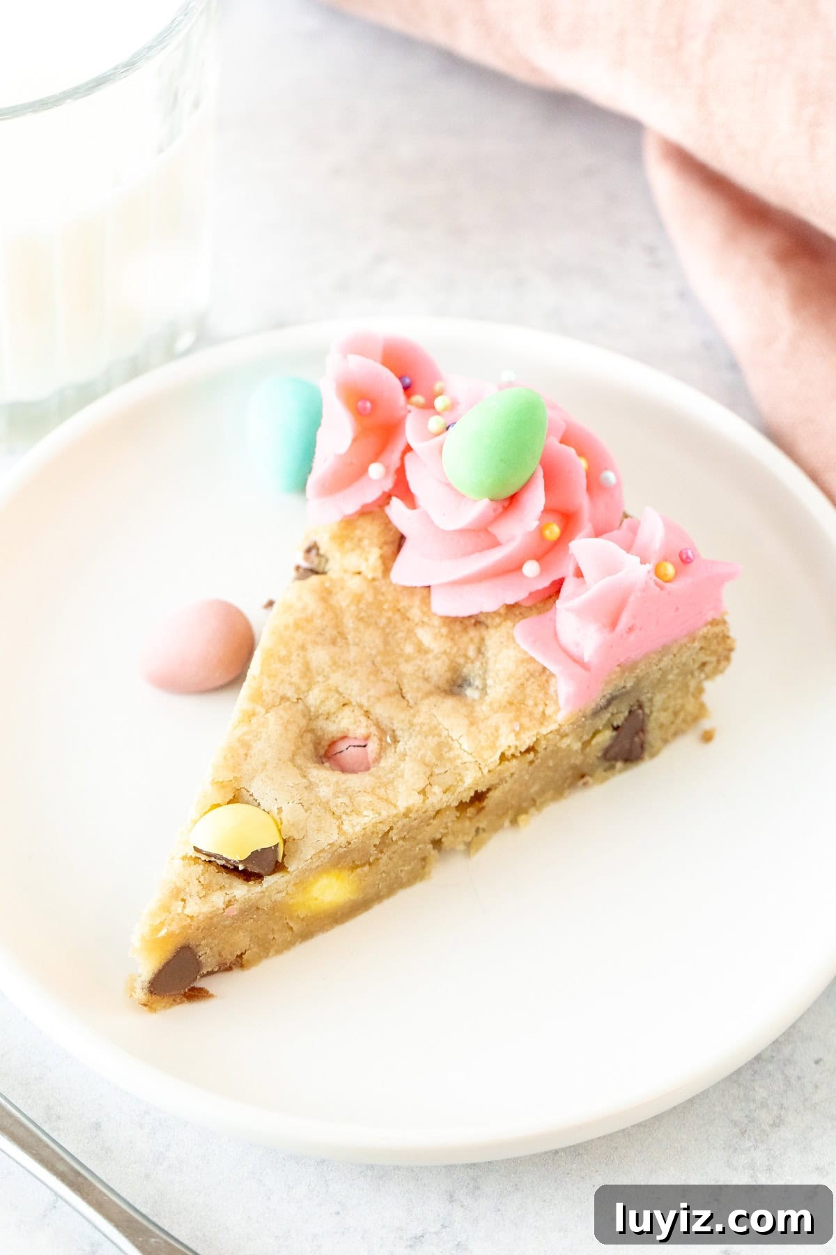 Easter Cookie Cake Recipe: Festive Cookie Cake for Spring Celebrations 4 Slice of Easter cookie cake decorated with pink frosting and a chocolate egg candy