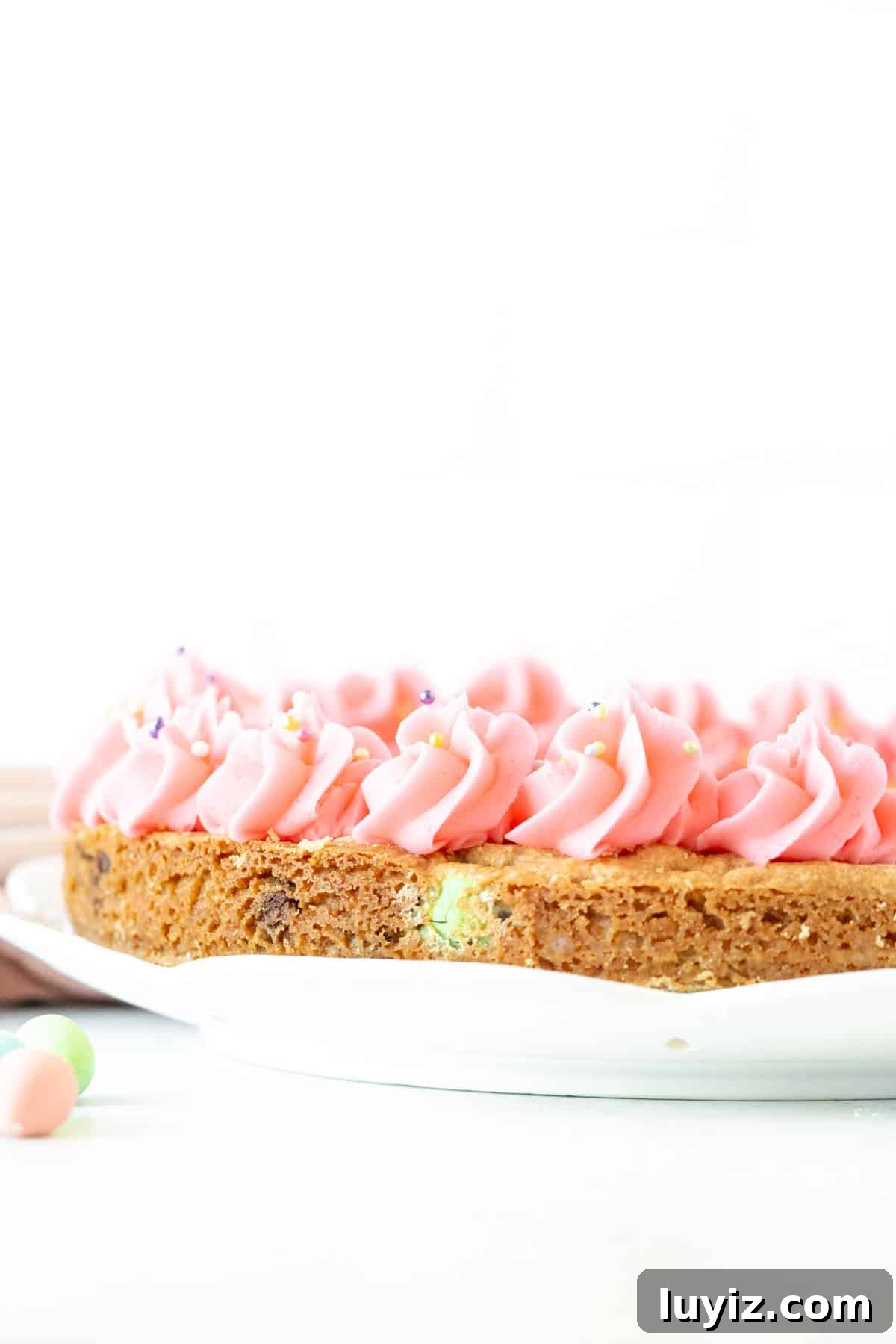Easter Cookie Cake Recipe: Festive Cookie Cake for Spring Celebrations 5 Cookie cake made with chocolate Easter eggs and decorated with vanilla frosting around the edges.