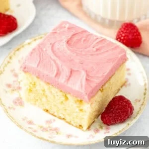 Slice of almond cake with raspberry frosting with a glass of milk