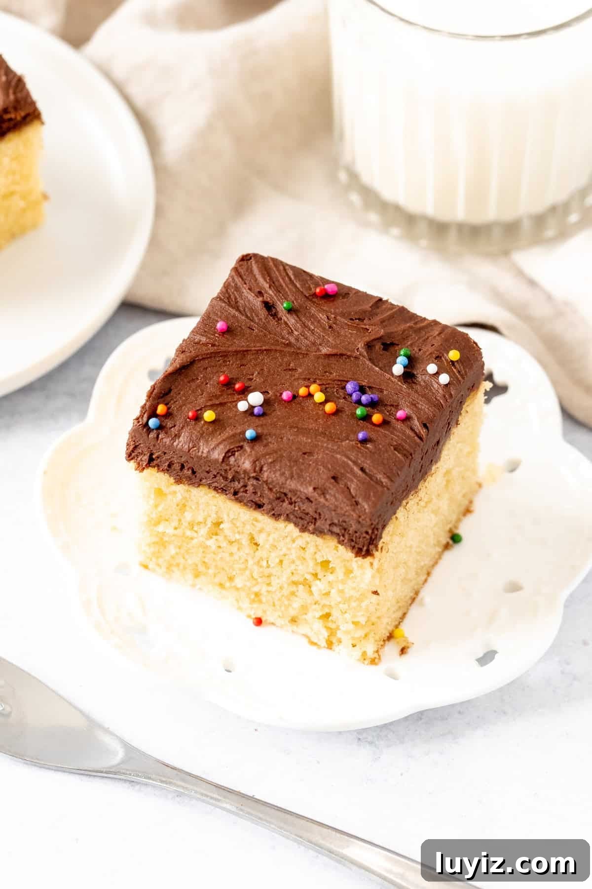 Moist Yellow Sheet Cake with Decadent Chocolate Frosting 9 Square slice of golden yellow cake with chocolate frosting with a glass of milk