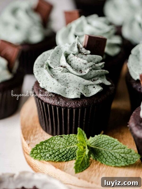Ultra-Moist Carrot Cake Cupcakes with Cream Cheese Frosting 8 Mint chocolate cupcakes topped with mint chocolate chip frosting and an Andes mint on a wood circular tray with mint leaves as decoration.