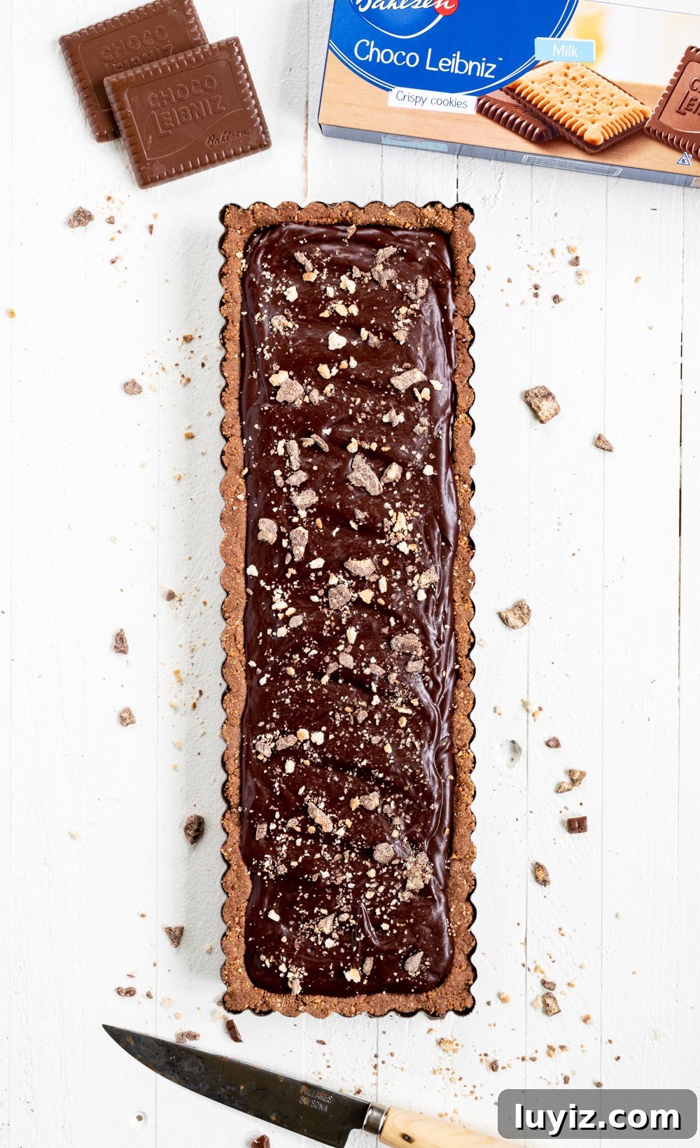 Decadent No-Bake Dark Chocolate Tart Recipe 3 No-bake Dark Chocolate Tart | Overhead image of No-Bake Dark Chocolate Tart with a box of the cookies above it and a cutting knife below