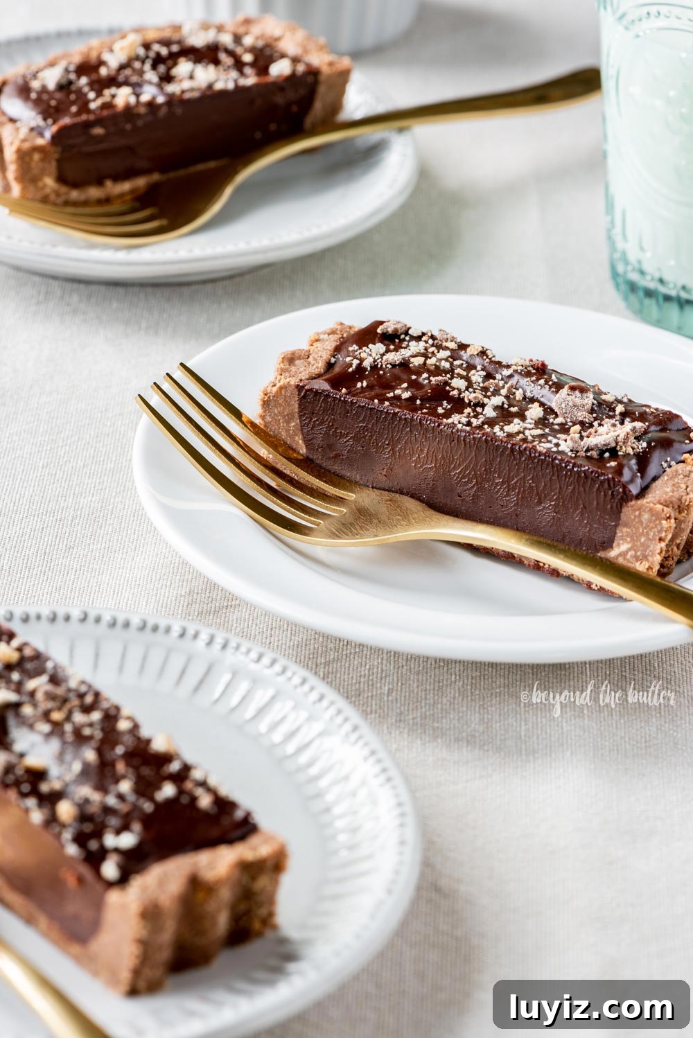 Decadent No-Bake Dark Chocolate Tart Recipe 4 No-bake Dark Chocolate Tart | Slices of no-bake dark chocolate tart on dessert plates with forks and a glass of milk