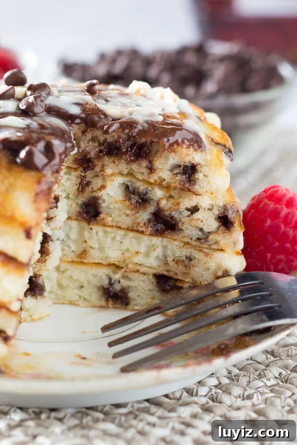 Fluffy Chocolate Chip Pancakes with Vanilla Syrup Recipe 3 A side view of a large stack of chocolate chip pancakes with a bite taken out of them.