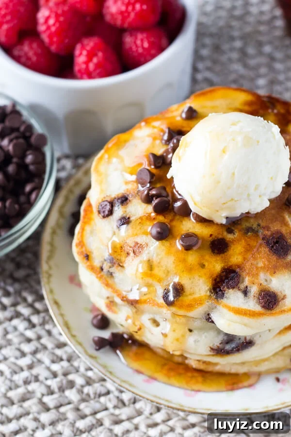Fluffy Chocolate Chip Pancakes with Vanilla Syrup Recipe 5 Overhead shot of a stack of fluffy chocolate chip pancakes topped with syrup, chocolate chips, and whipped butter.