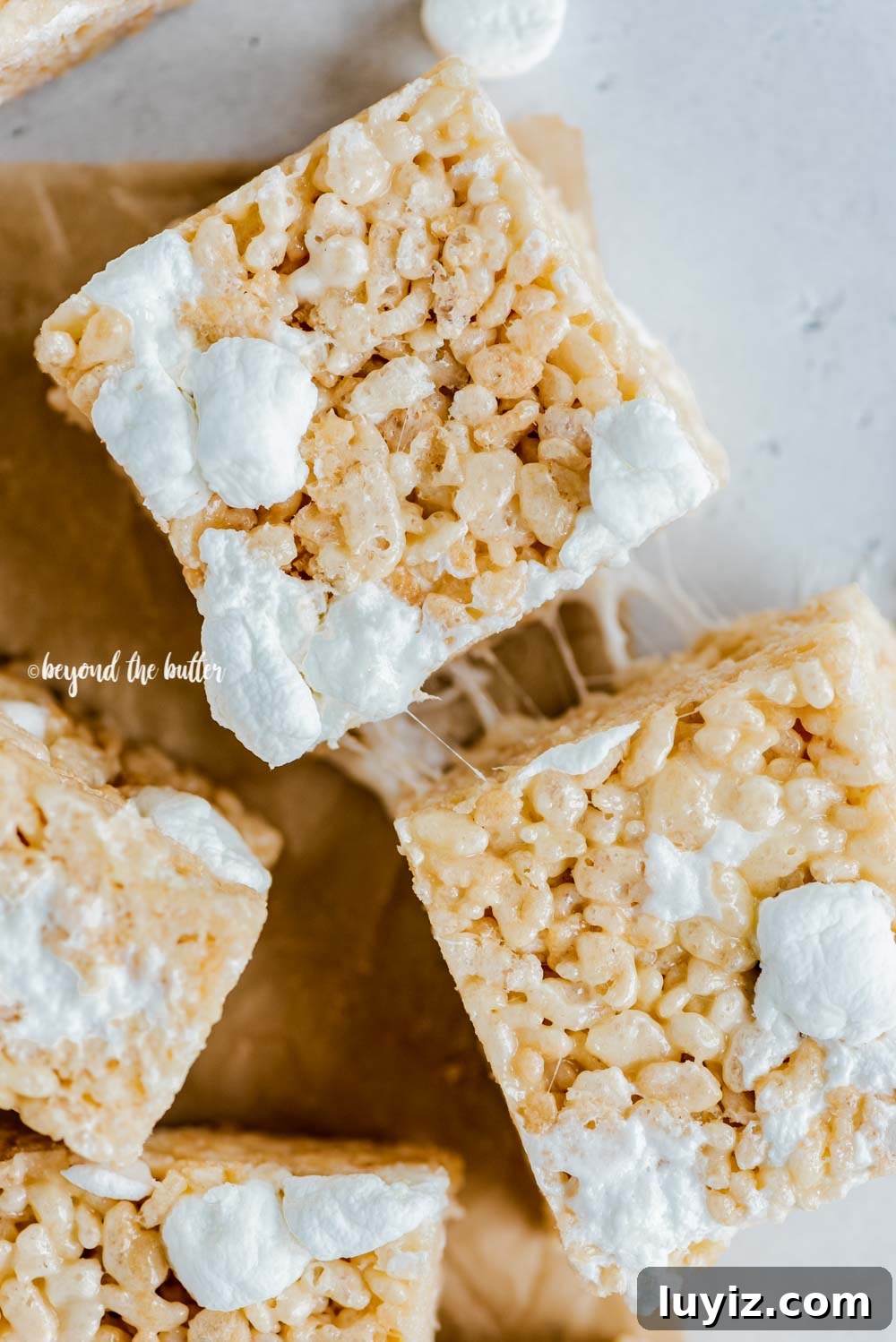 Perfectly Chewy Rice Krispie Treats Recipe 6 Overhead image of just cut rice krispie treats on parchment paper with a knife placed to the right