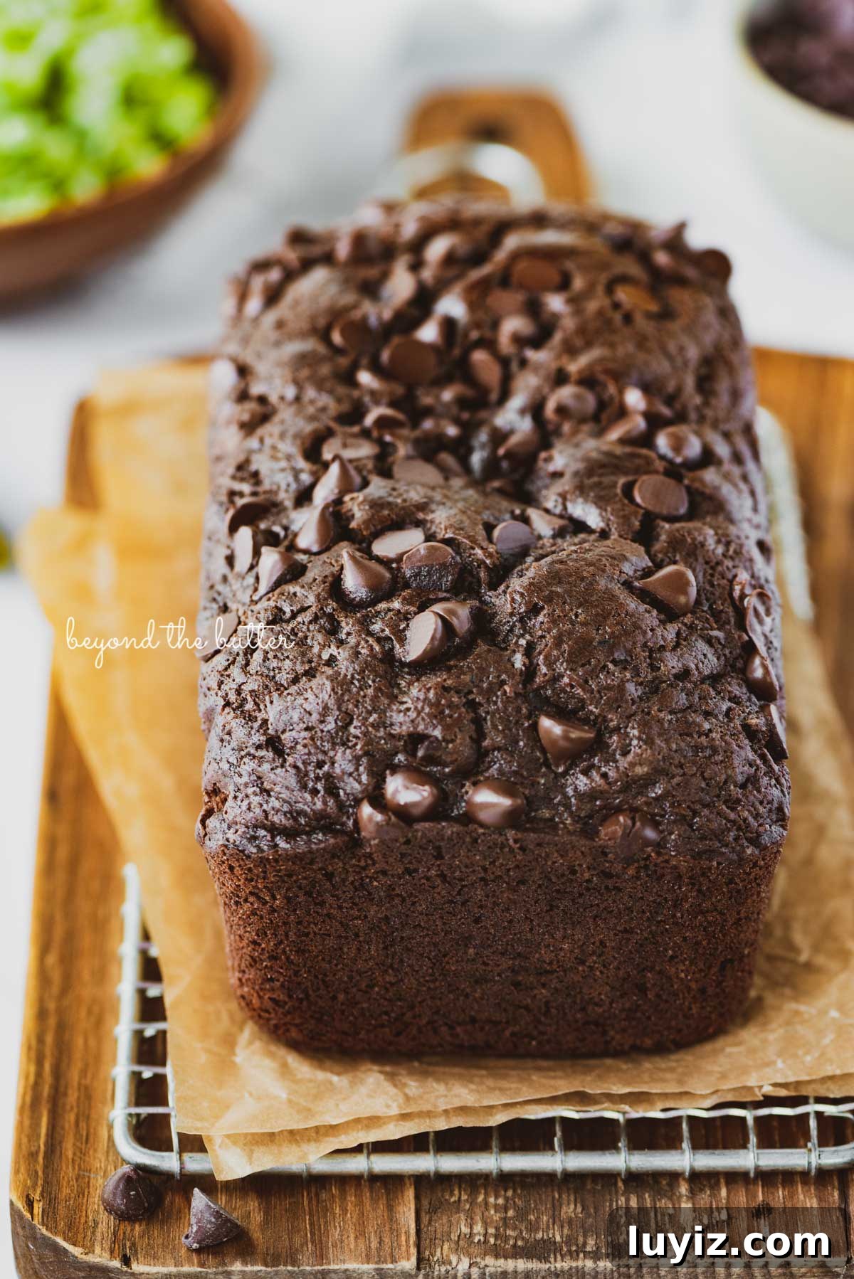 One-Bowl Chocolate Zucchini Quick Bread Recipe 3 Sliced chocolate zucchini bread on a cutting board with a knife | © Beyond the Butter®