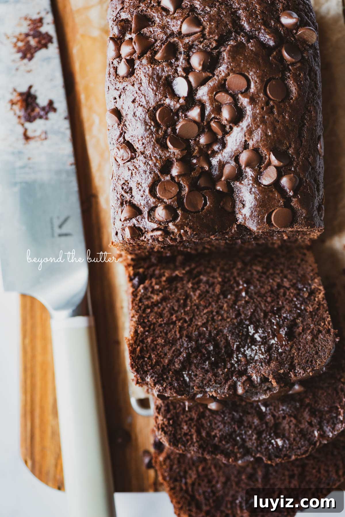 One-Bowl Chocolate Zucchini Quick Bread Recipe 4 Sliced chocolate zucchini bread on a cutting board with a knife | © Beyond the Butter®