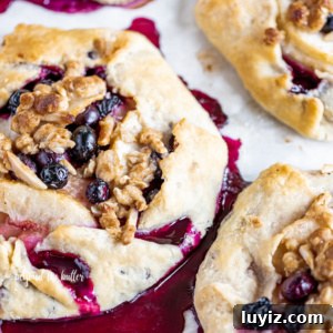 Blueberry Peach Galettes: Flaky Summer Fruit Hand Pies 14 Blueberry peach galettes on parchment paper.