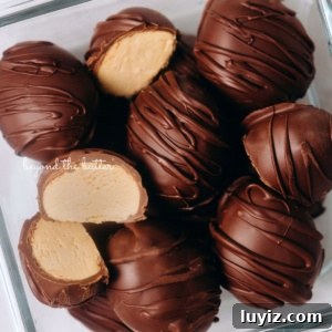 Peanut Butter Eggs Dipped in Chocolate: Homemade Candy Recipe 14 Chilled chocolate covered peanut butter eggs drizzled with more chocolate randomly placed in a glass container with two cut in half on white background.