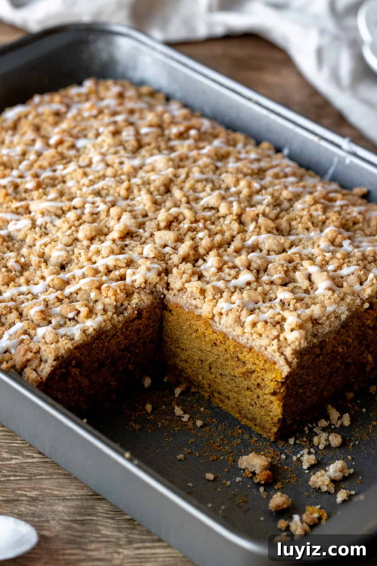 Pumpkin Spice Coffee Cake Recipe for Fall Gatherings 3 Pan of pumpkin coffee cake with streusel topping and drizzle of glaze
