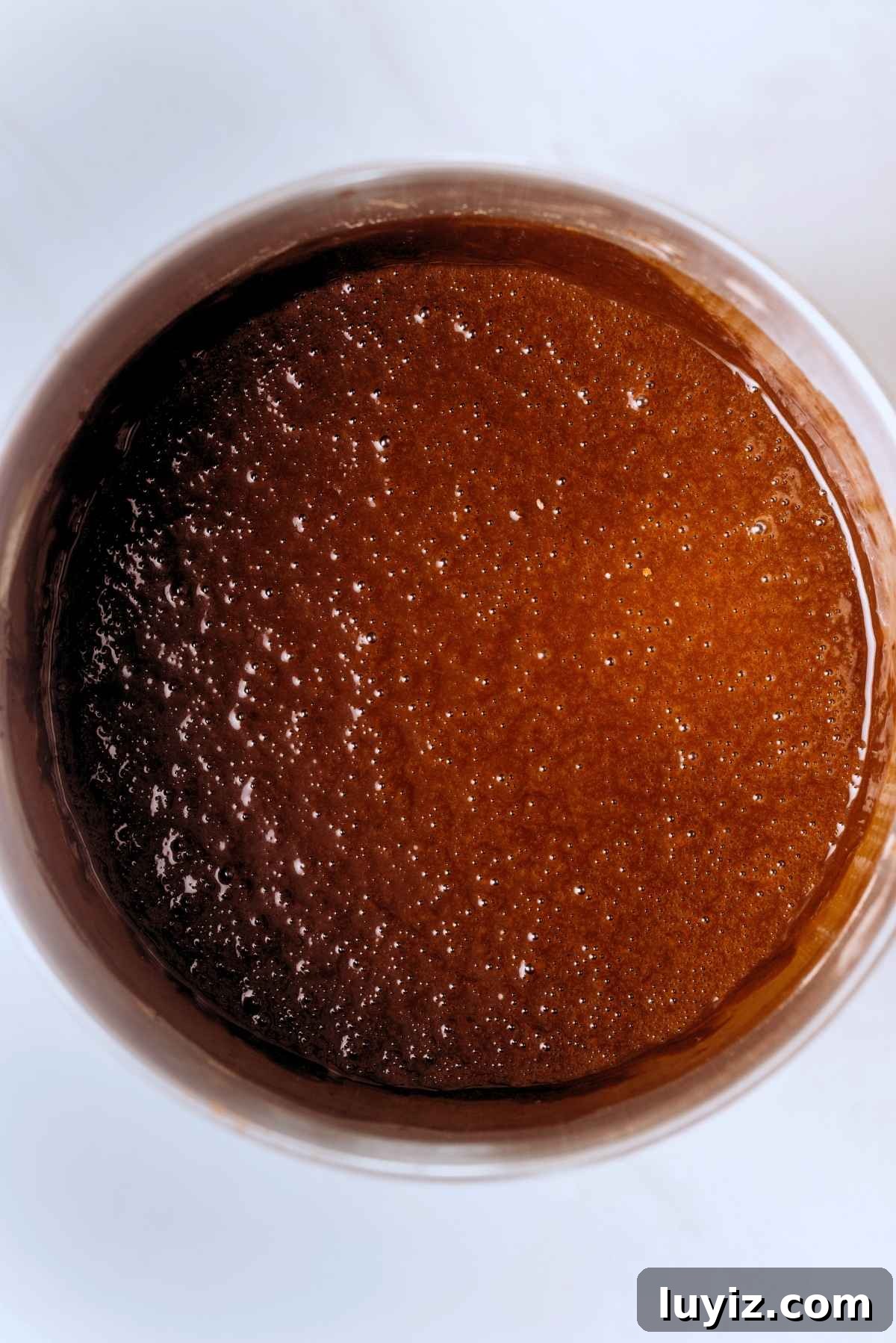 Decadent Chocolate Cake with Oreo Buttercream Frosting 11 Chocolate cake batter in a stainless steel mixing bowl on a white background.