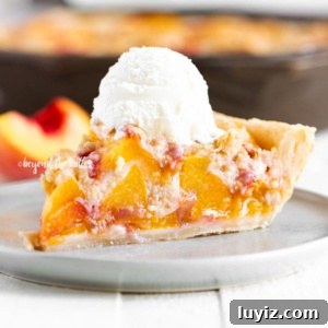 Brown Sugar Peach Crumble Pie Recipe for Tender Juicy Peaches 11 Slice of brown sugar peach crumble pie on dessert table with rest of pie in background.