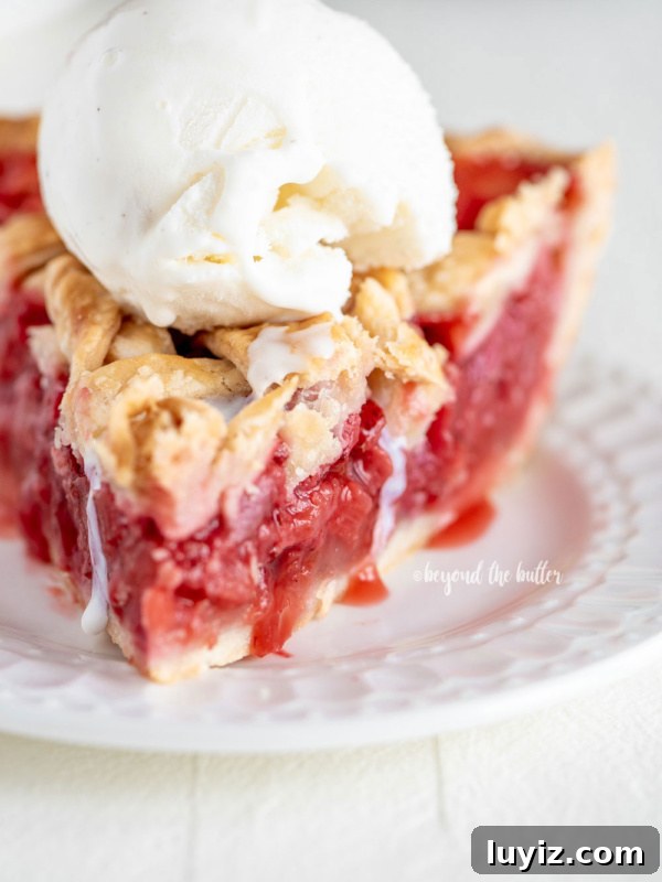Brown Sugar Peach Crumble Pie Recipe for Tender Juicy Peaches 7 Slice of strawberry rhubarb pie with scoop of vanilla ice cream on dessert plate on white wood table.