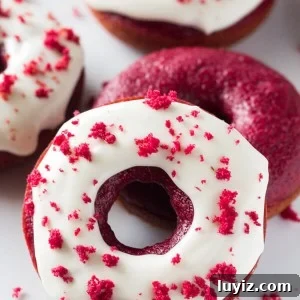 Baked Red Velvet Doughnuts. These moist doughnuts have the perfect cake doughnut crumb, a delicious red velvet flavor & a cream cheese glaze. www.justsotasty.com