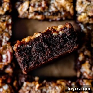 Salted Pecan Pie Brownies Recipe: Gooey Chocolate with Crunch 14 Salted pecan pie brownies placed on brown parchment paper with the center brownie placed on its side on an angle.