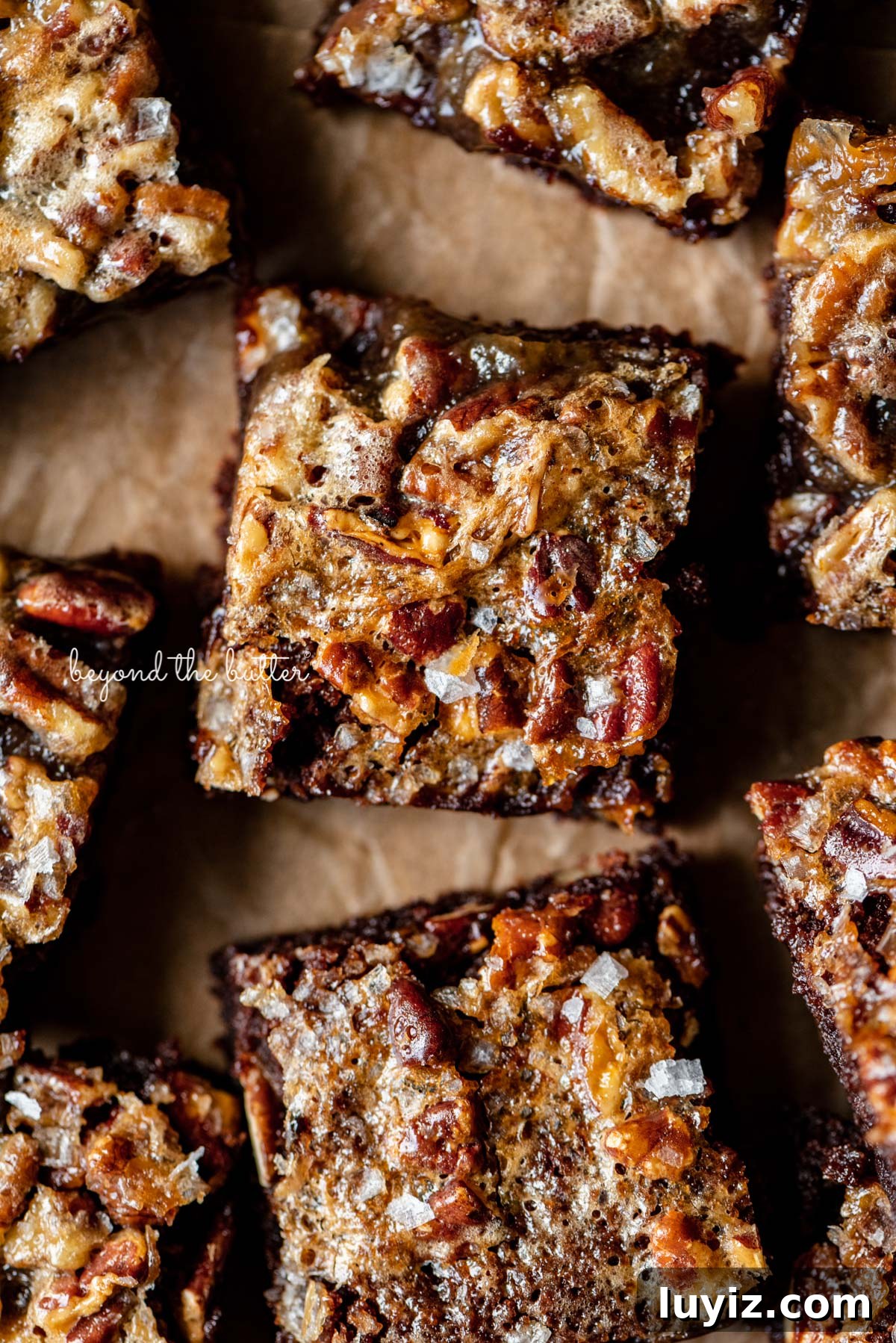 Salted Pecan Pie Brownies Recipe: Gooey Chocolate with Crunch 3 Salted pecan pie brownies placed on brown parchment paper | © Beyond the Butter®