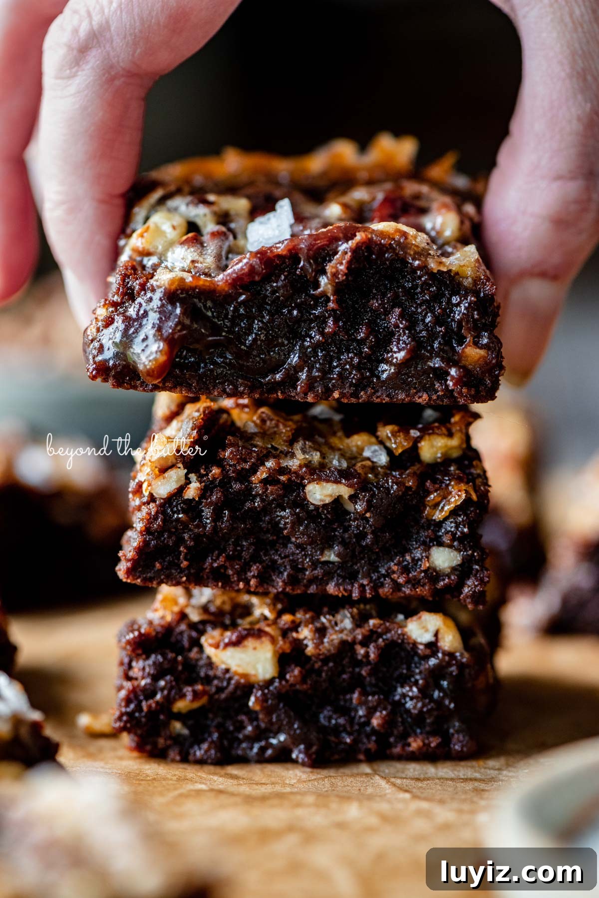Salted Pecan Pie Brownies Recipe: Gooey Chocolate with Crunch 4 Stacking the best salted pecan pie brownies on brown parchment paper | © Beyond the Butter®