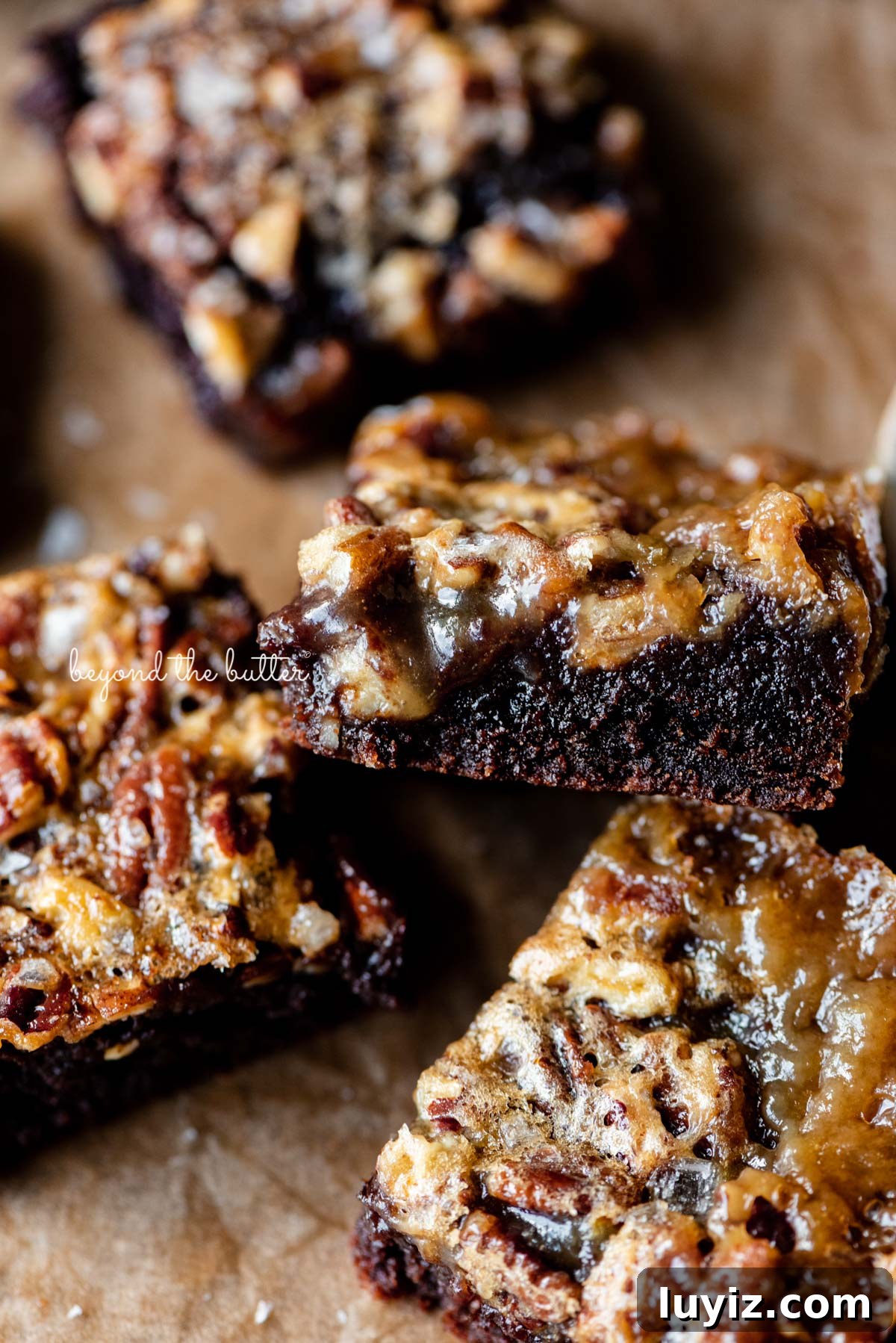 Salted Pecan Pie Brownies Recipe: Gooey Chocolate with Crunch 5 Salted pecan pie brownies placed on brown parchment paper | © Beyond the Butter®