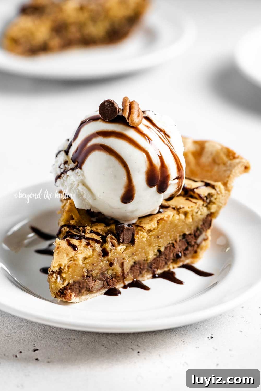 Ultimate Chocolate Chip Pie Recipe: Gooey, Crispy, and Irresistible 2 Angled closeup image of Chocolate Chip Pie with a scoop of vanilla ice cream on top that's drizzled with chocolate syrup