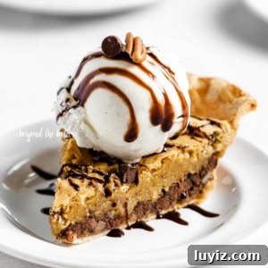 Ultimate Chocolate Chip Pie Recipe: Gooey, Crispy, and Irresistible 13 Angled closeup image of Chocolate Chip Pie with a scoop of vanilla ice cream on top that's drizzled with chocolate syrup.