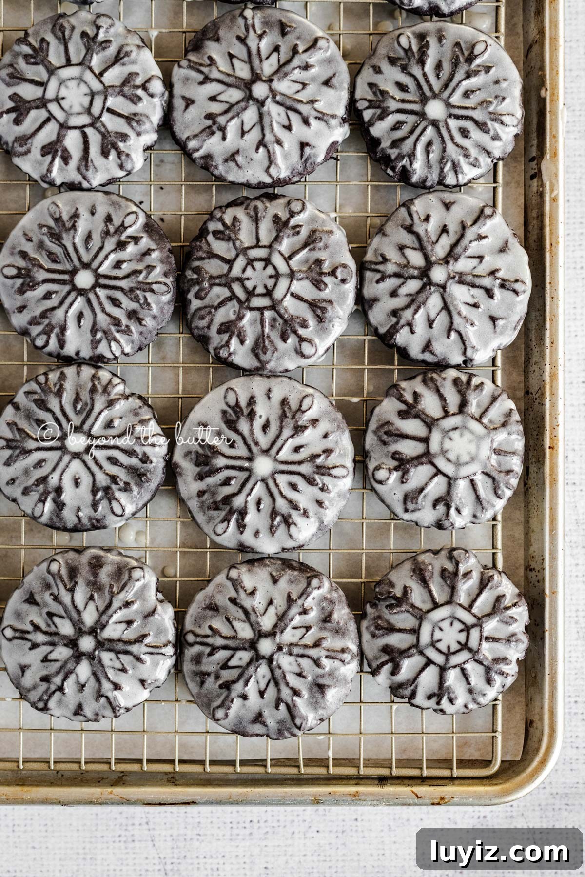 Oreo Snowflake Cookies Recipe: Holiday Sandwich Cookies 3 Overhead image of homemade oreo snowflake cookies on a baking sheet and wire cooling rack | All Images © Beyond the Butter®