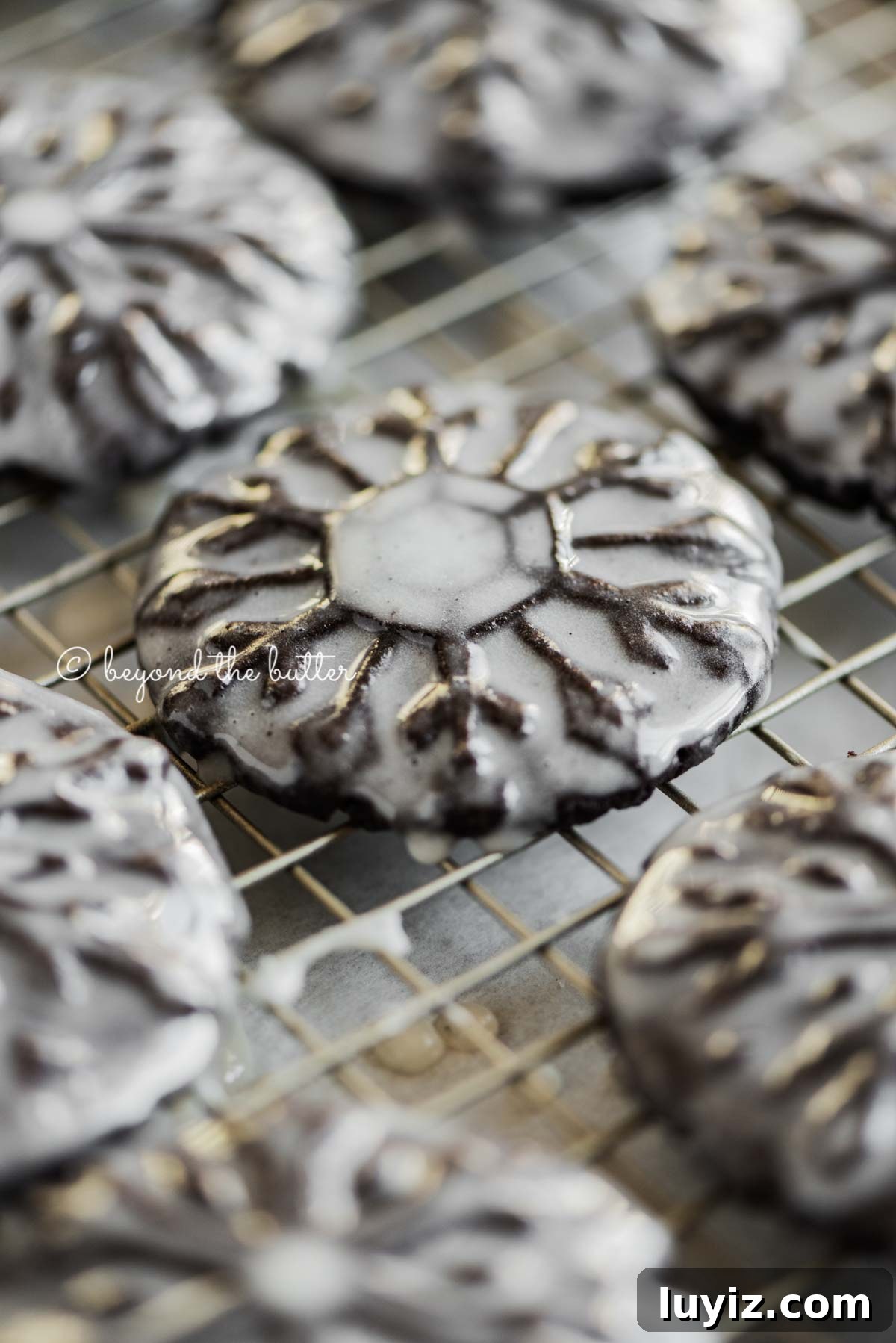 Oreo Snowflake Cookies Recipe: Holiday Sandwich Cookies 4 Angled closeup image of homemade oreo snowflake cookies on a wire cooling rack | All Images © Beyond the Butter®