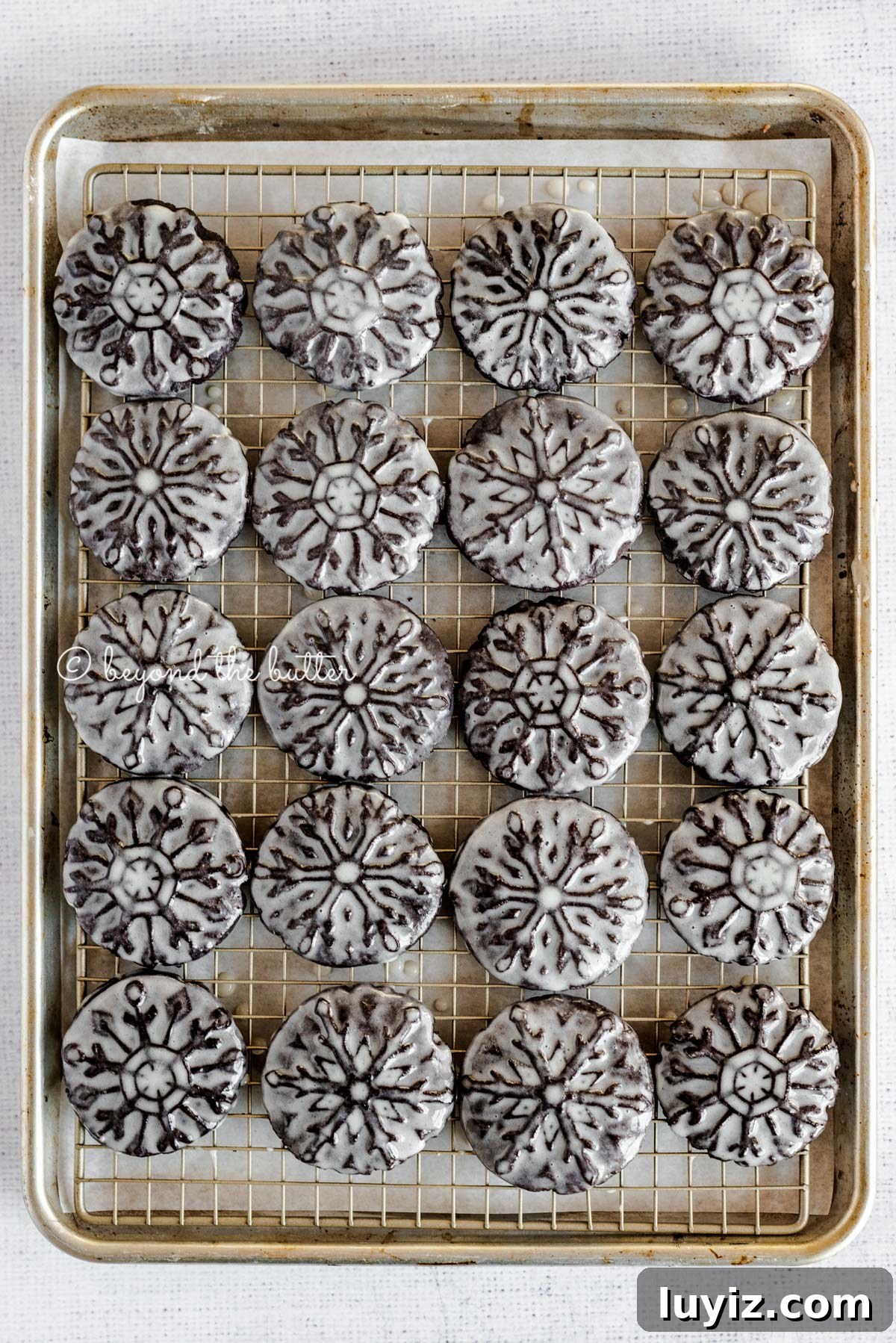 Oreo Snowflake Cookies Recipe: Holiday Sandwich Cookies 5 Overhead image of homemade oreo snowflake cookies on a baking sheet and wire cooling rack | All Images © Beyond the Butter®
