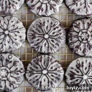 Oreo Snowflake Cookies Recipe: Holiday Sandwich Cookies 8 Overhead image of homemade glazed oreo snowflake cookies on a wire cooling rack.