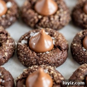 Chocolate Caramel Blossom Cookies: Gooey Centers & Crisp Edges 7 Angled image of Chocolate Caramel Blossoms on cookie sheet on white parchment paper.