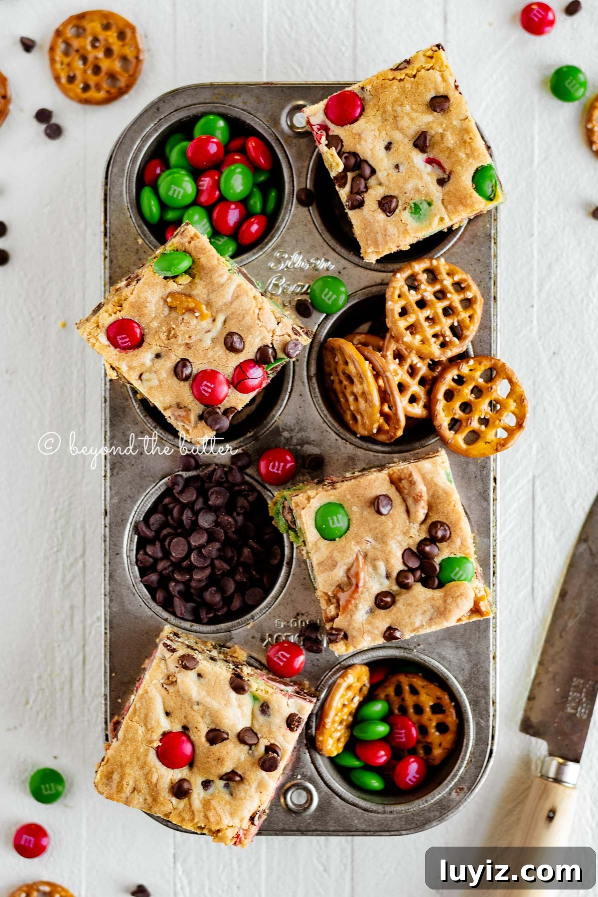 Holiday Chocolate Chip Cookie Bars for Festive Baking 3 Overhead image of chocolate chip cookie bars cut into squares and placed on top of a cupcake tin with candy | All Images © Beyond the Butter®