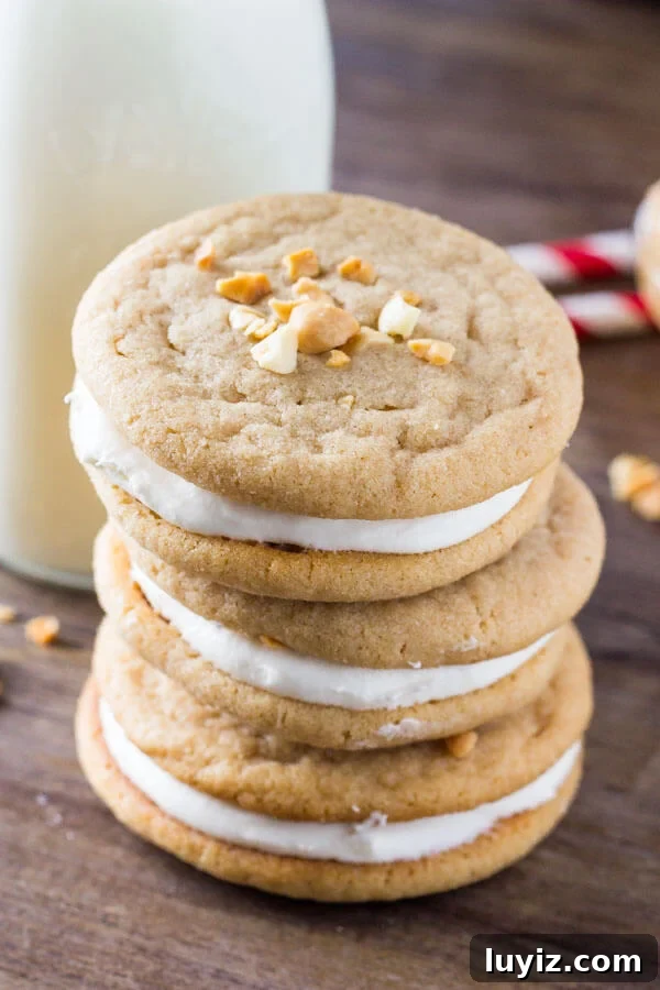 Fluffernutter Sandwich Cookies: Peanut Butter & Marshmallow Treats 3 Stack of 3 fluffernutter cookies with a glass of milk and 2 straws in the background.