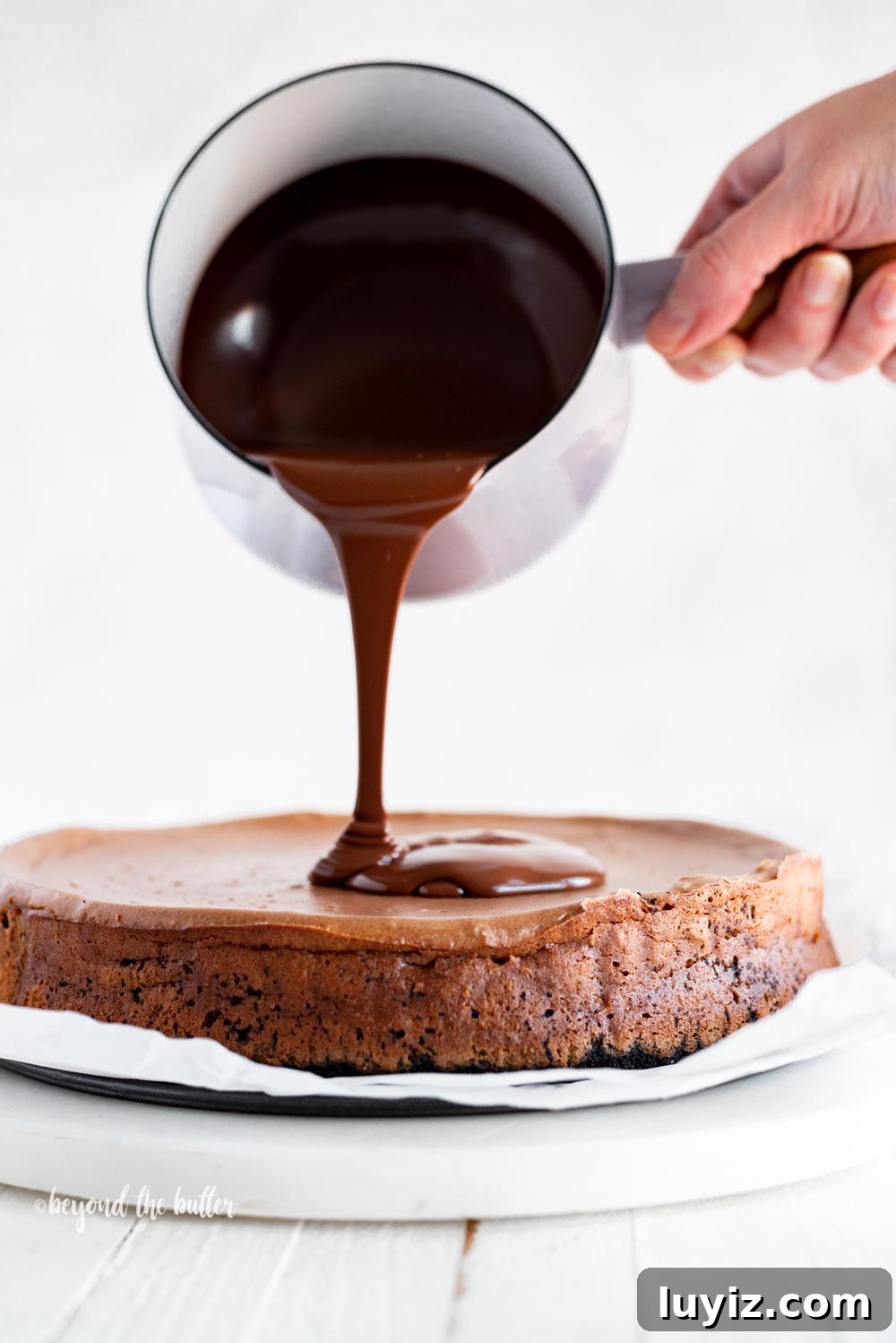 Triple Chocolate Mocha Cheesecake Recipe — Decadent Espresso Chocolate Cheesecake 3 Pouring dark chocolate ganache over top of Triple Chocolate Mocha Cheesecake | All Images © Beyond the Butter, LLC