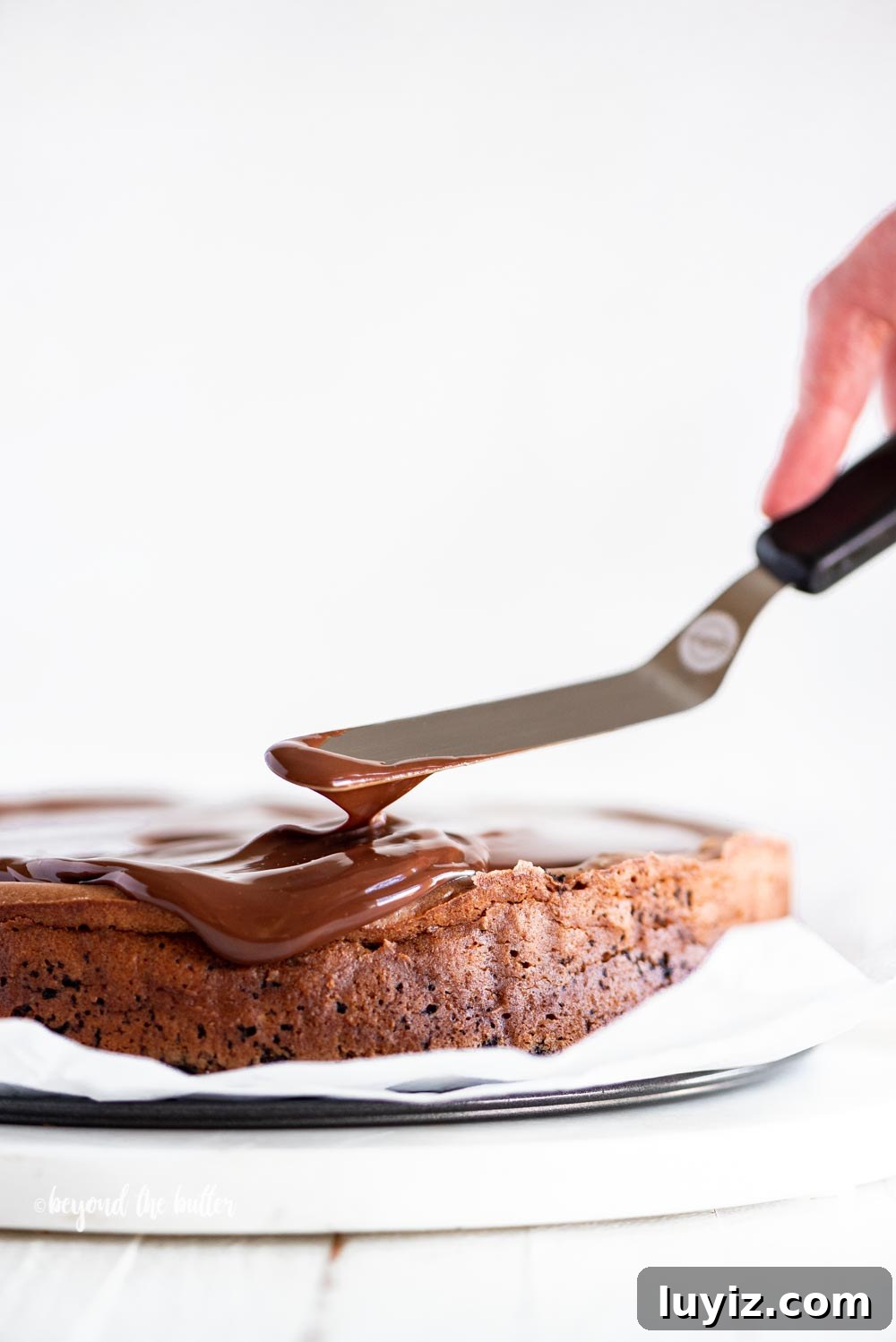 Triple Chocolate Mocha Cheesecake Recipe — Decadent Espresso Chocolate Cheesecake 7 Using an offset spatula to spread out the dark chocolate ganache on top of the Triple Chocolate Mocha Cheesecake | All Images © Beyond the Butter, LLC