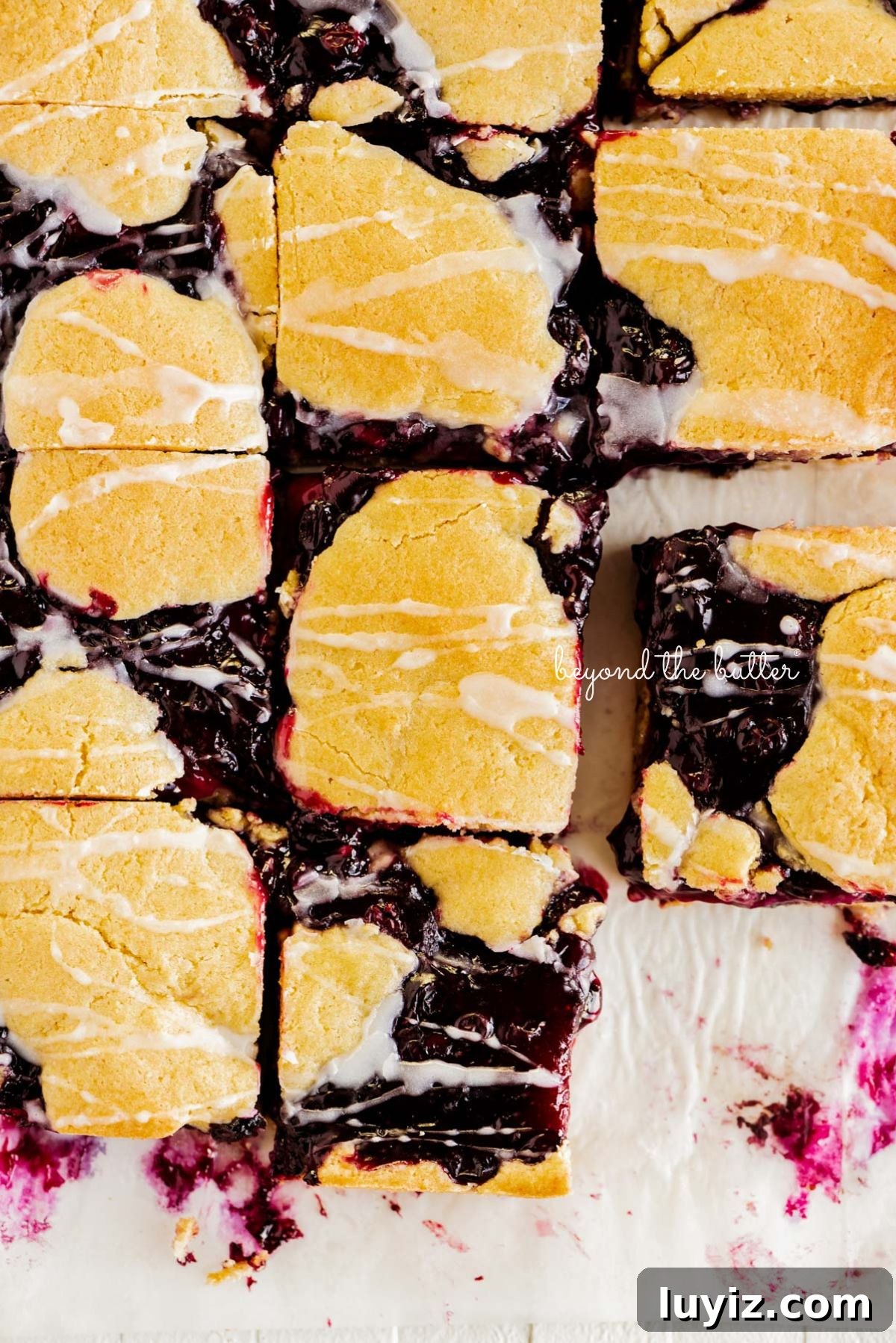 Blueberry Swirl Coffee Cake Recipe with Streusel Topping 13 Slices of blueberry swirl coffee cake squares on a white parchment paper background.