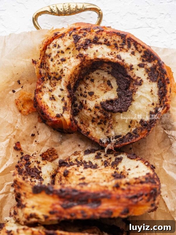 Blueberry Swirl Coffee Cake Recipe with Streusel Topping 14 Sliced chocolate croissant loaf placed on brown parchment paper lined gold tray and white background.