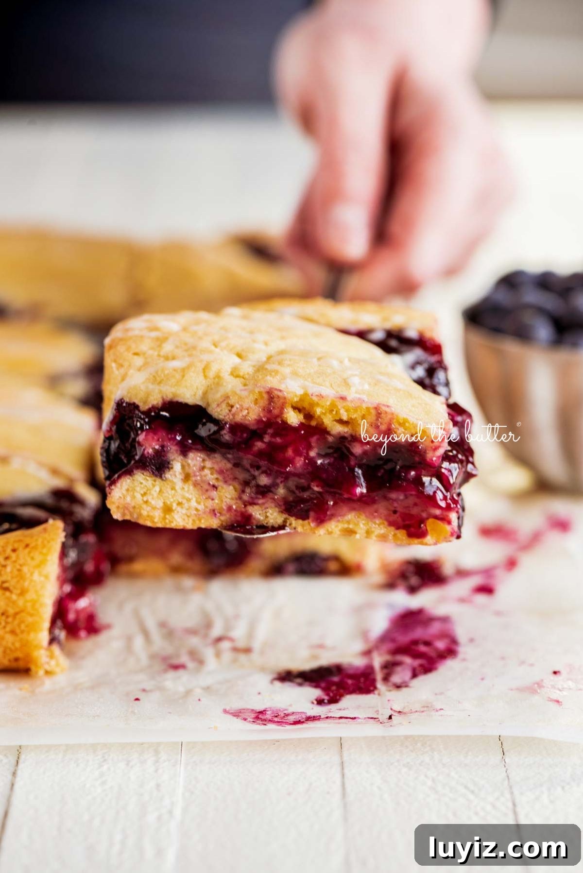 Blueberry Swirl Coffee Cake Recipe with Streusel Topping 3 Serving a slice of freshly baked blueberry swirl coffee cake on wood table.