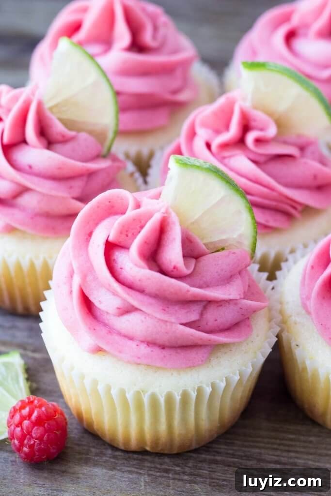 Lime Cupcakes with Raspberry Buttercream Frosting 2 Group of lime cupcakes with raspberry frosting with a lime slice on top.