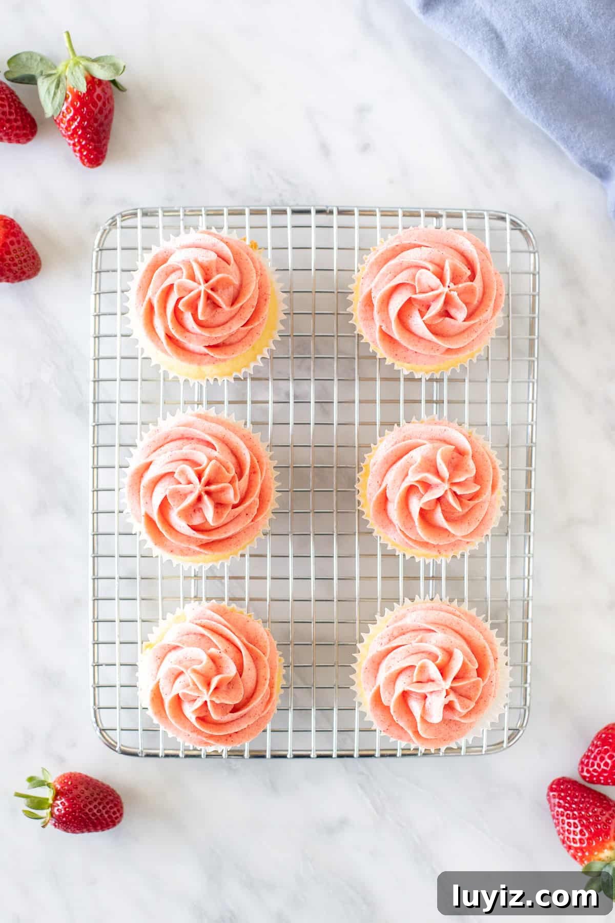 Vanilla Cupcakes with Fresh Strawberry Buttercream Frosting 3 6 cupcakes with pink frosting on a wire cooling rack rack