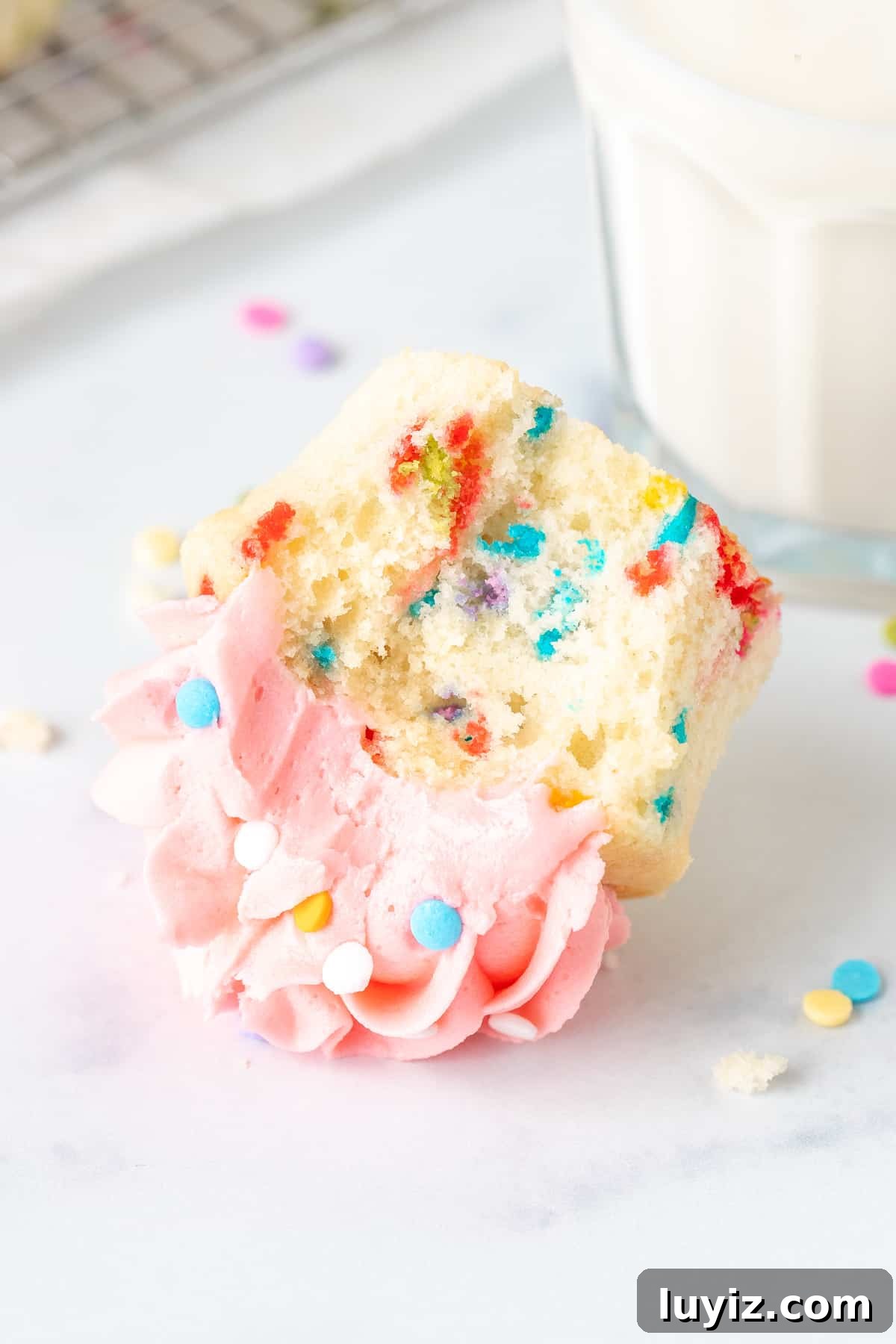 Funfetti Sprinkle Cupcakes: Classic Celebration Cupcake Recipe 4 Funfetti cupcake with a bite taken out, on its side