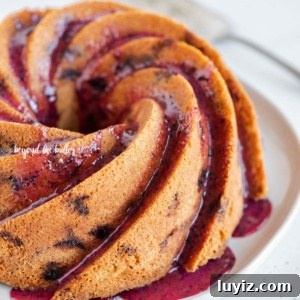 Moist Blueberry Bundt Cake with Lemon Glaze 13 Angled image of super easy blueberry bundt cake with blueberry glaze drizzled over the top.