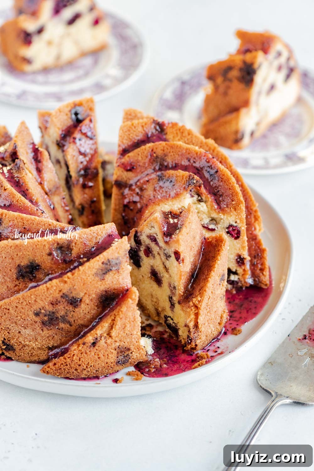 Moist Blueberry Bundt Cake with Lemon Glaze 4 Angled image of sliced blueberry bundt cake with blueberry glaze drizzled over the top | All Images © Beyond the Butter, LLC