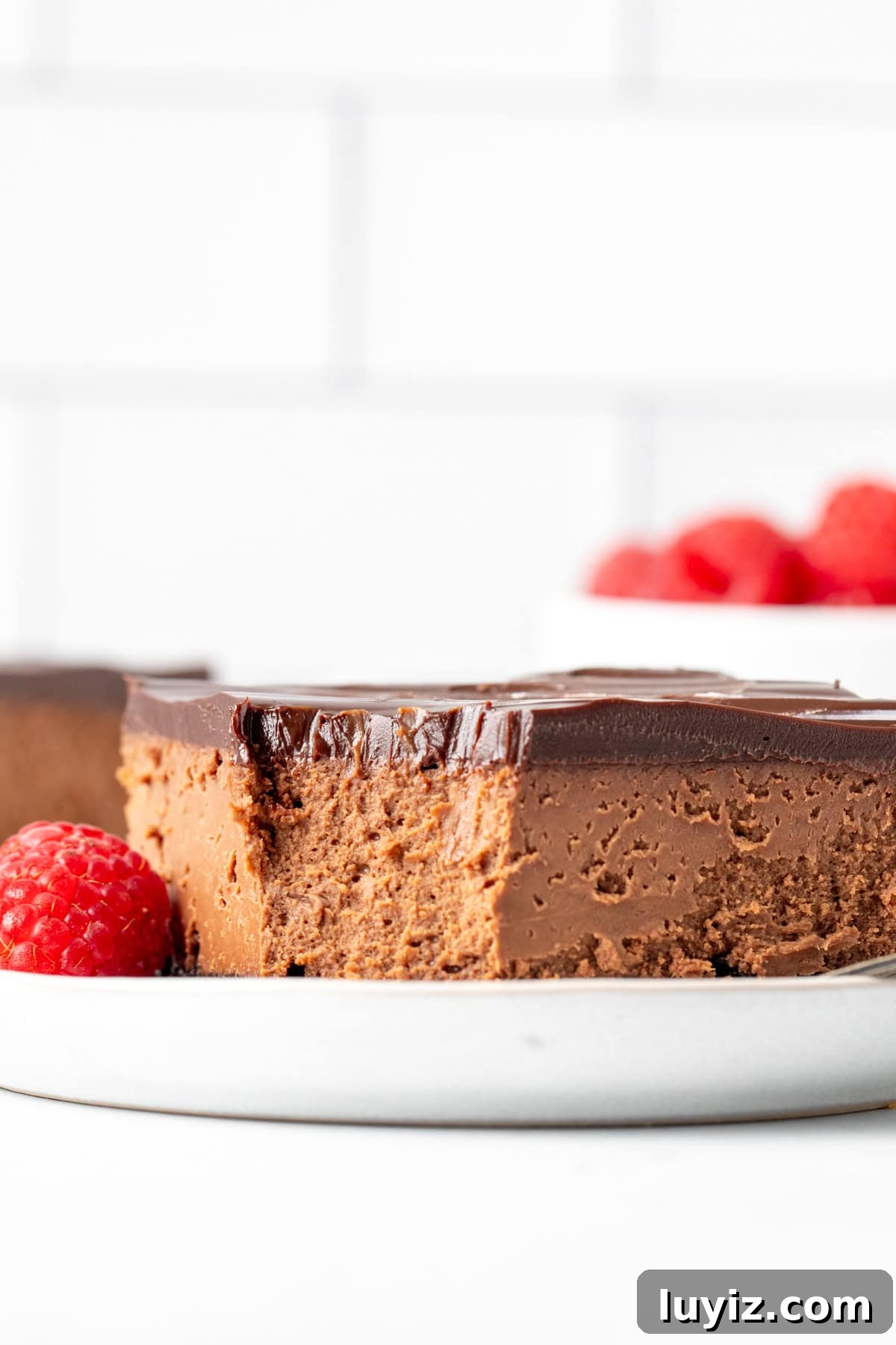 Decadent Chocolate Cheesecake Bars Recipe for Chocolate Lovers 3 Chocolate cheesecake square with a bite taken out of it on a plate.