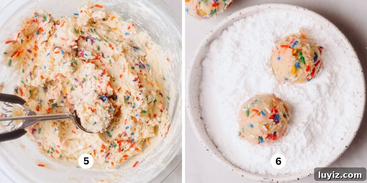 Funfetti Butter Cookies Recipe with Sprinkle-Filled Shortbread 7 Scooping funfetti cookie dough out of a large glass bowl with a cookie scoop then rolling each cookie dough ball in a white ceramic shallow bowl of powdered sugar on a white background.