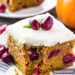 Cranberry Pumpkin Cake with Cream Cheese Frosting Recipe 5 Slice of Cranberry Pumpkin Cake with Cream Cheese Frosting with a bite taken out of it and a fork resting on the side of the plate.
