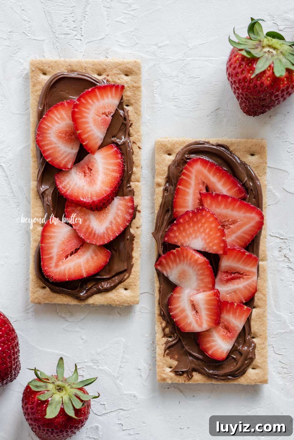 Mini Strawberry Nutella Tartlets: Bite-Sized Dessert Recipe 4 Image of strawberries and nutella spread over top of 2 graham crackers | All Images © Beyond the Butter®